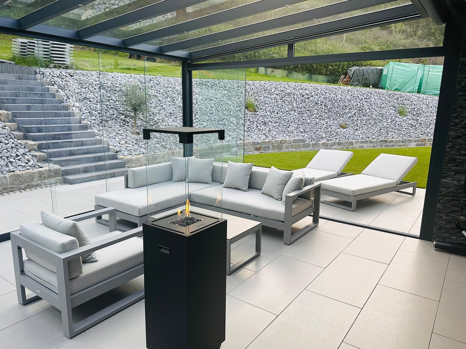 Überdachte Terrasse mit großformatigen Platten, Lounge und Feuerstelle