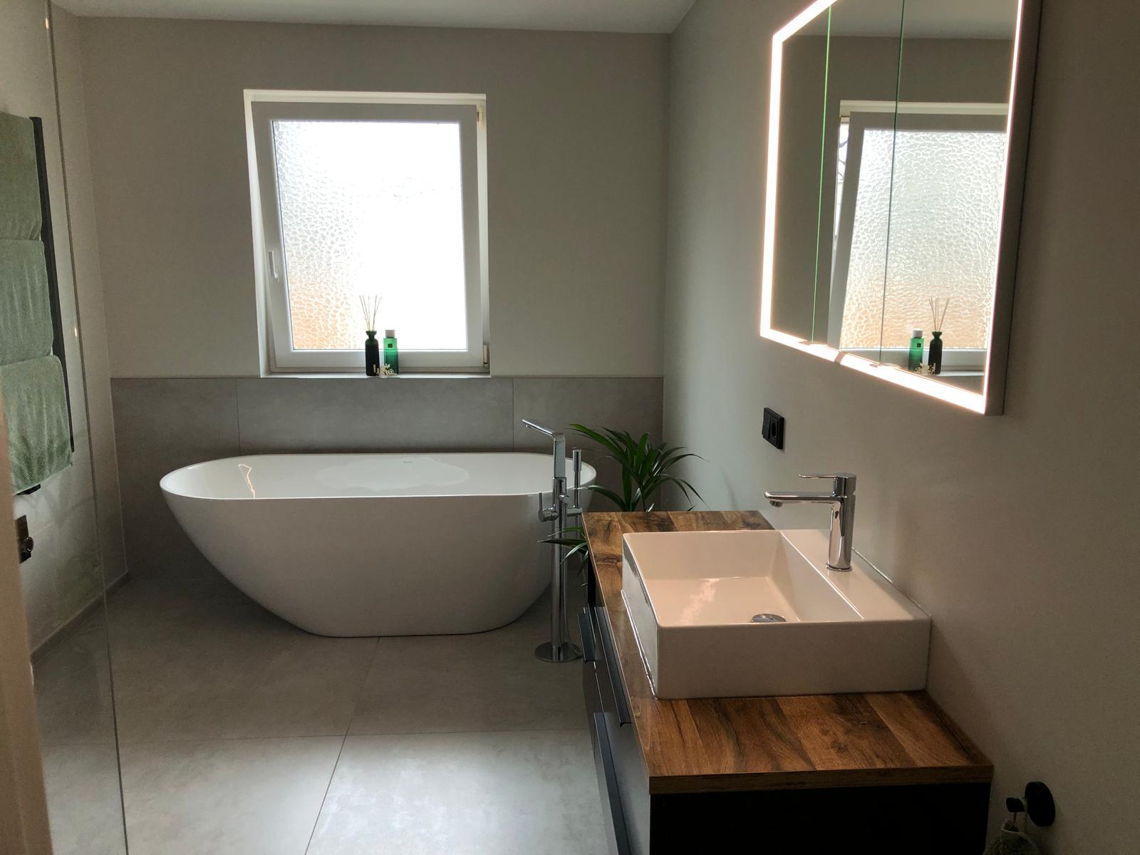 Helles Bad mit freistehender Badewanne, Waschtisch und Holzablage