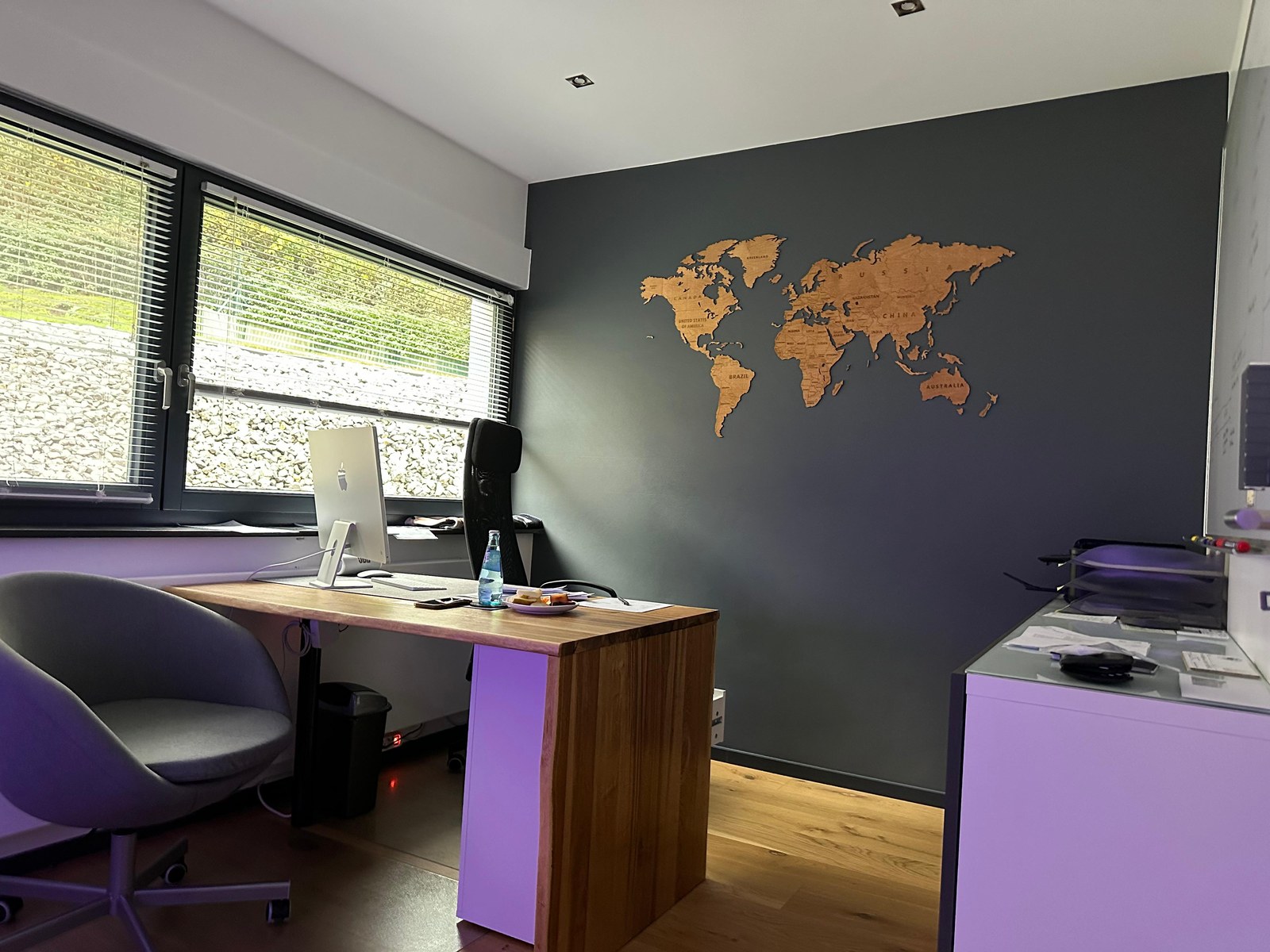 Renoviertes Büro mit dunkler Akzentwand und Weltkarte