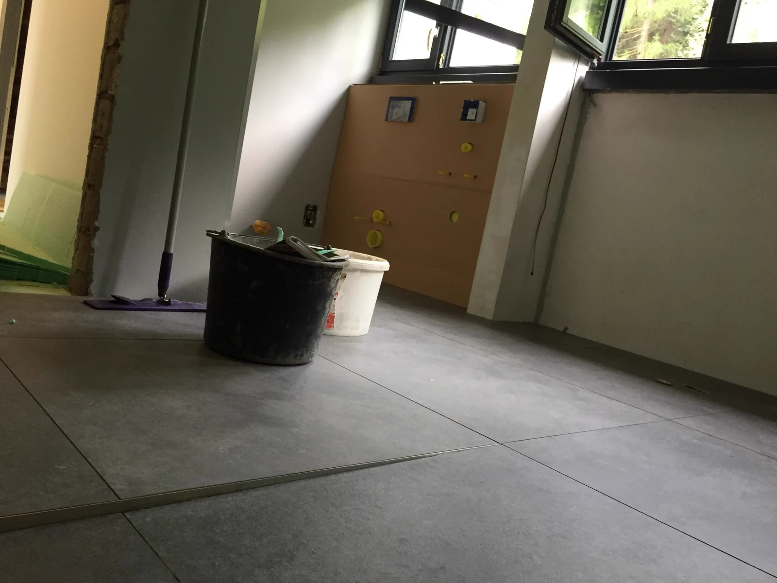 Fliesenarbeiten mit großformatigen grauen Bodenfliesen